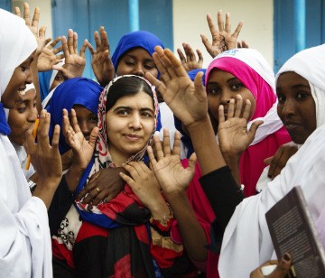 photo of Malala surrounded by girls with their hands raised