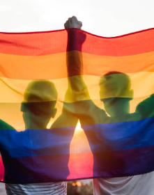 two people silhouetted behind a rainbow flag